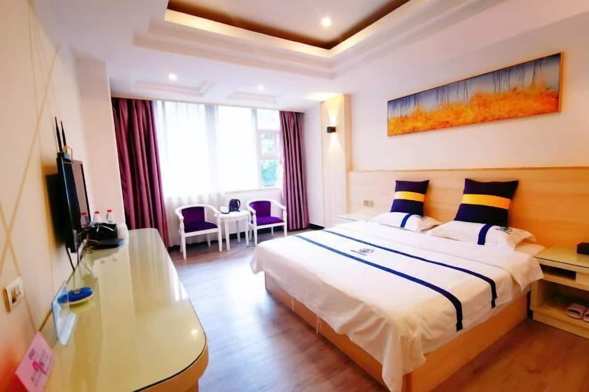 Una habitación de hotel con una cama grande, un escritorio, una silla y un cuadro en la pared.