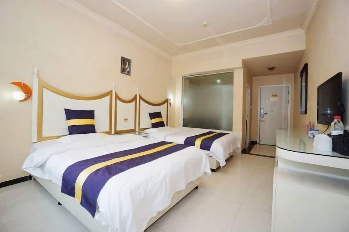 Habitación de hotel con dos camas, un escritorio, un televisor y una puerta que da a un baño.