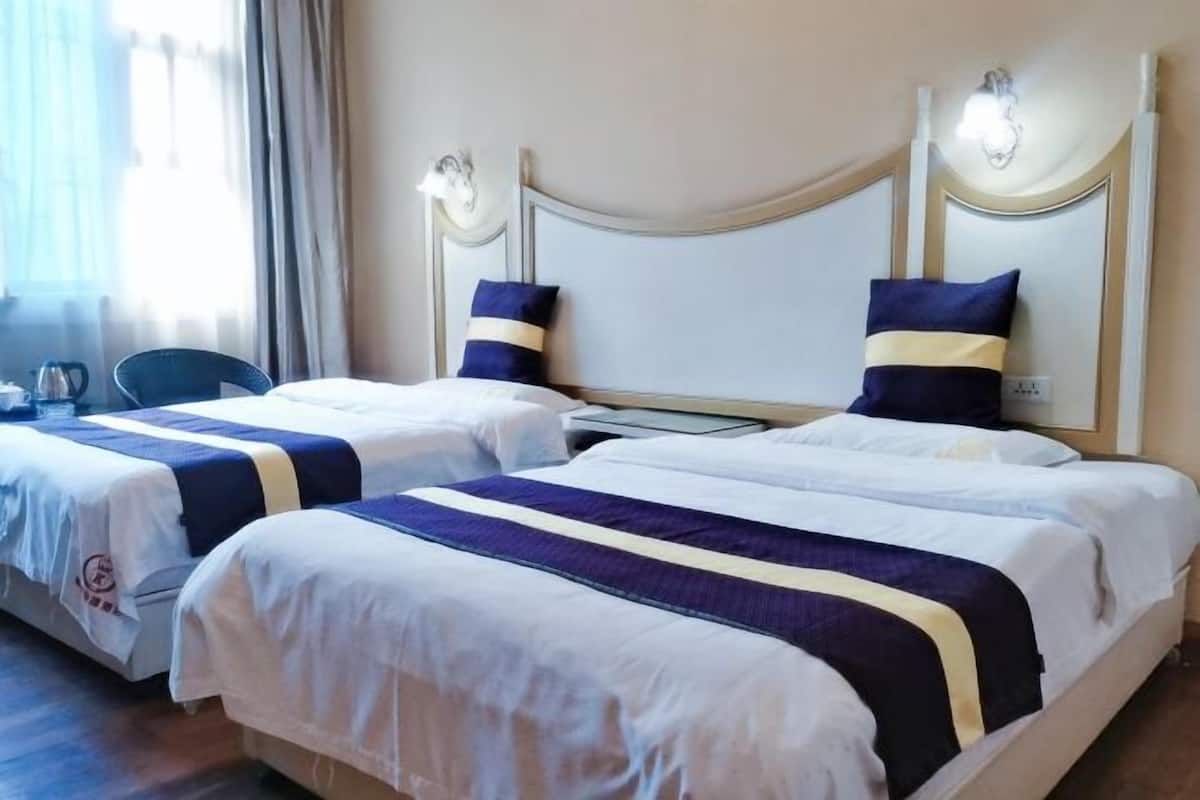 Habitación de hotel con dos camas, cada una con cabecera y lámparas de noche.