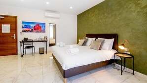 Une chambre d’hôtel avec un grand lit, un bureau avec une chaise, un miroir et un tableau au mur.