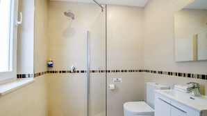 A modern bathroom with a glass-enclosed shower, a toilet, and a sink with a mirror above it. - Deluxe Double Room with side sea view - South Wind Guesthouse (Marsaxlokk)
