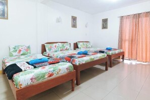 A room with three wooden beds, each with floral bedding, and a window with curtains. - Golden Success Hotel I by RedDoorz (Paniqui)