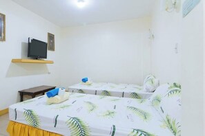 A hotel room with two beds, a television on a shelf, and a small table with a towel and a blue item. - Golden Success Hotel I by RedDoorz (Paniqui)