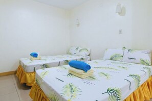 A room with two beds, each with a yellow skirted base and a botanical-themed bedspread. - Golden Success Hotel I by RedDoorz (Paniqui)