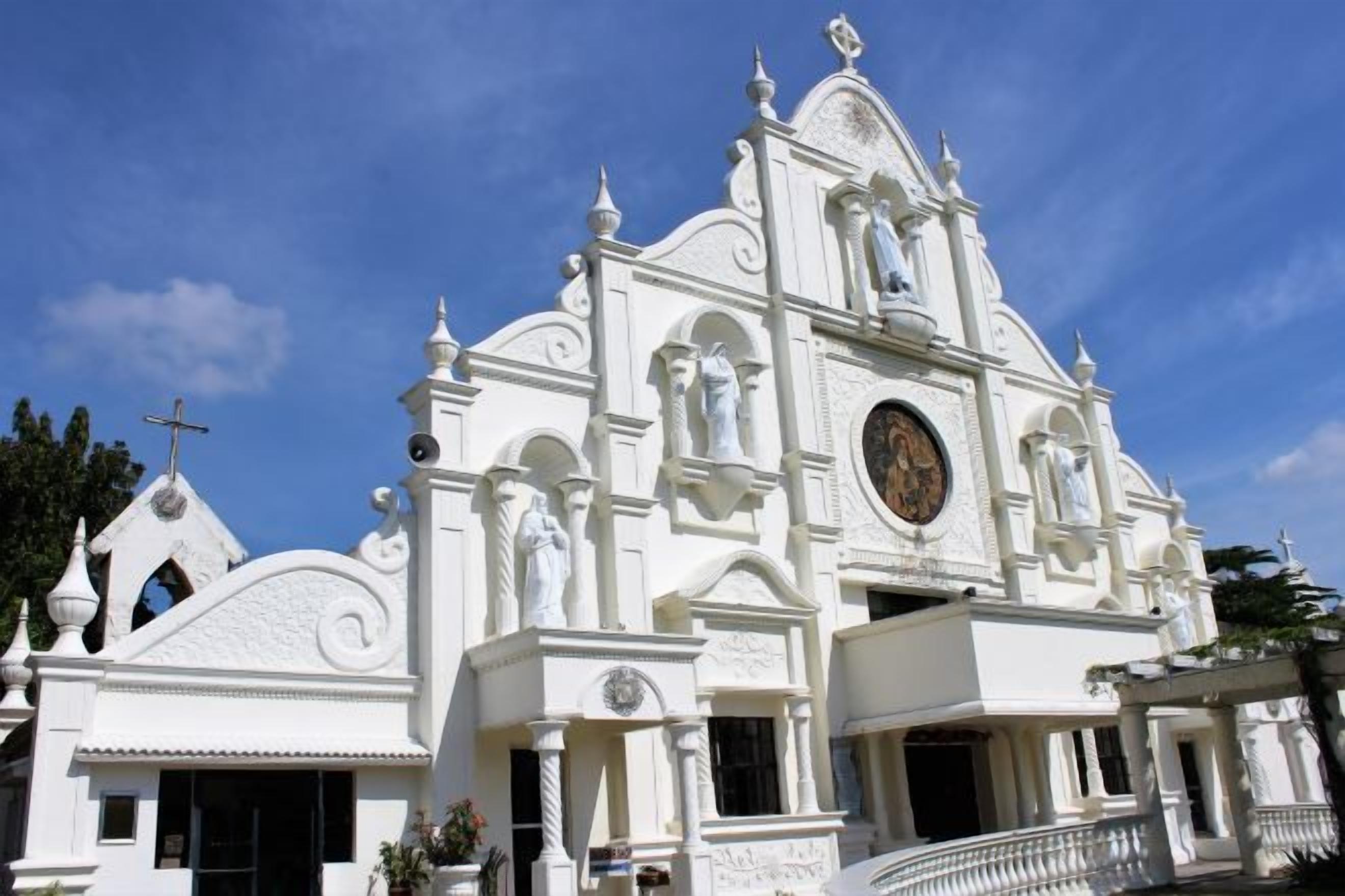 A white church with a clock, a cross, and a bell tower.