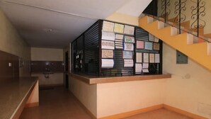 A reception area with a counter displaying various notices and a staircase with a metal railing. - Golden Success Hotel I by RedDoorz (Paniqui)