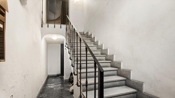 A staircase with a black metal railing and marble steps. - Colosseum Street Haven (ROMA)