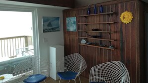 A room with a wooden wall, a white chair, a blue chair, and a shelf with decorative items.