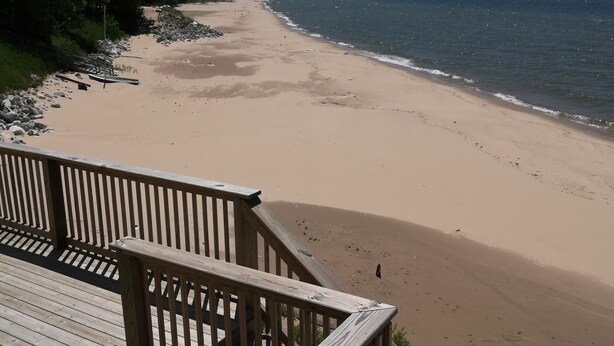 A wooden deck overlooking a sandy beach with a clear sky.