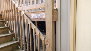 A wooden staircase leading to a cottage entrance with a sign that reads "WELCOME TO THE COTTAGE."