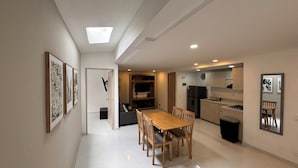 A modern kitchen with a dining area, a built-in TV, and a refrigerator.