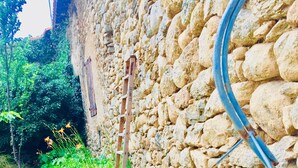 A rustic outdoor area with a stone wall, a metal ladder, and a bicycle wheel. - Maison Charmante au Cœur du Conflent (Sahorre)