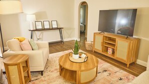 Een woonkamer met een bank, salontafel, tv-meubel en een lamp.