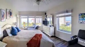 Ein Schlafzimmer mit Bett, Nachttisch, Lampe und Blick ins Freie.