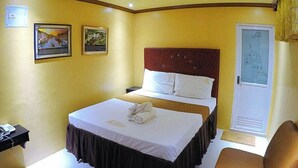 Une chambre d’hôtel comprenant un lit, une table de chevet et une porte dotée d’un panneau en verre dépoli.