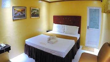 A hotel room with a bed, bedside table, and a door with a frosted glass panel.