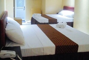 A hotel room with two beds, each with a white and brown bedspread, a bedside table with a phone, and a door leading to the hallway. - Reddoorz Plus @ Taj Hotel Tuguegarao (Tuguegarao)