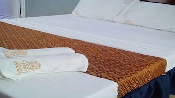 A neatly made bed with a patterned bedspread and two towels with a logo.