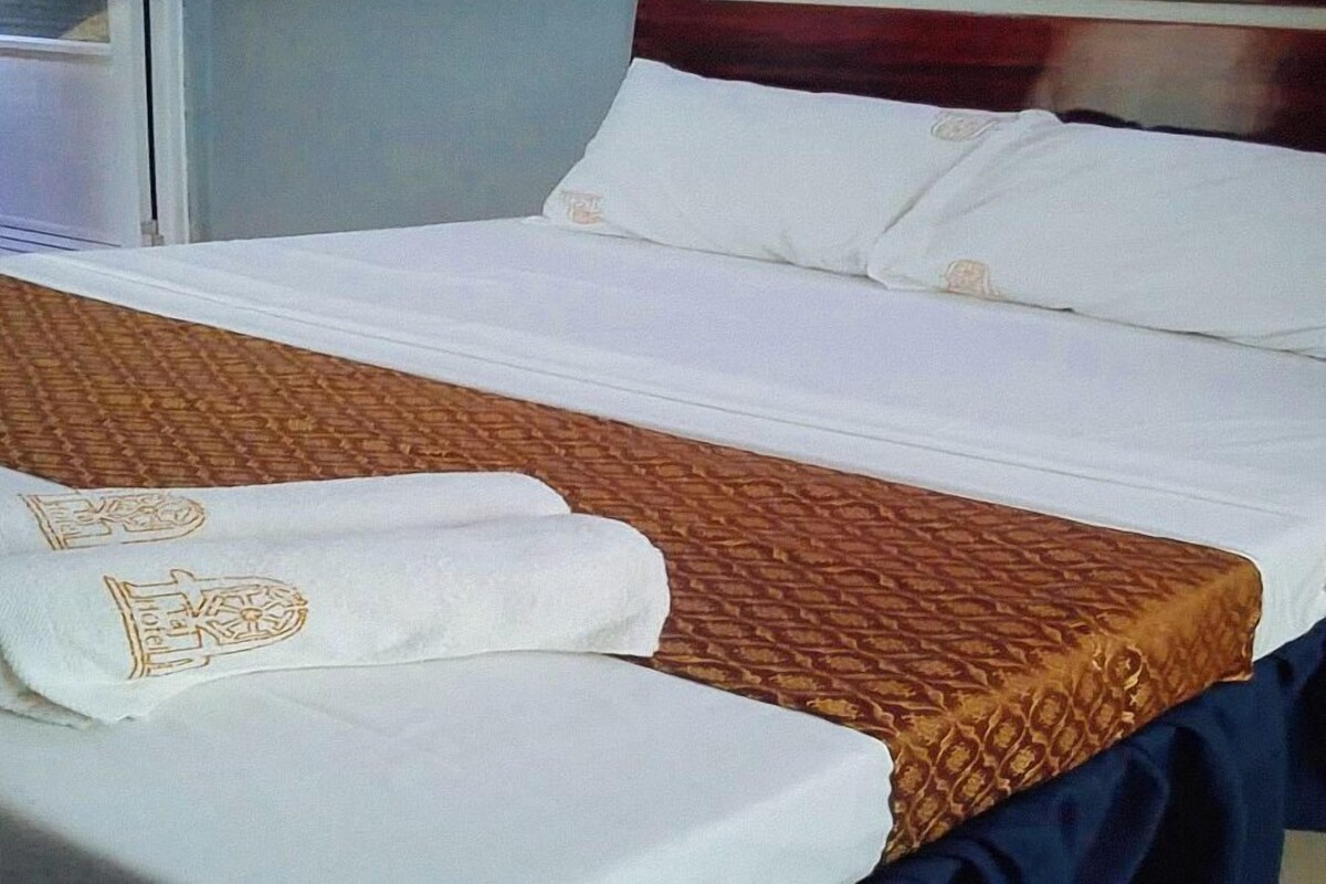 A neatly made bed with a patterned bedspread and pillows.