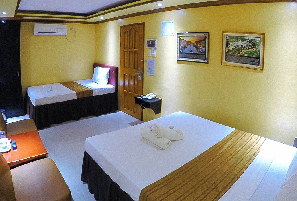 A hotel room with two beds, a desk, and a telephone.