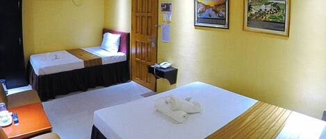 A hotel room with two beds, a desk, and a telephone.