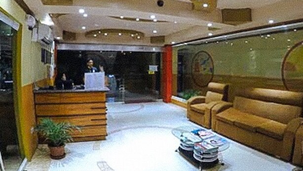 Un hall d’entrée avec un comptoir de réception, un canapé, une table basse et une plante en pot.