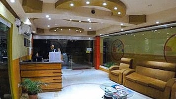 A lobby with a reception desk, a sofa, a coffee table, and a potted plant.