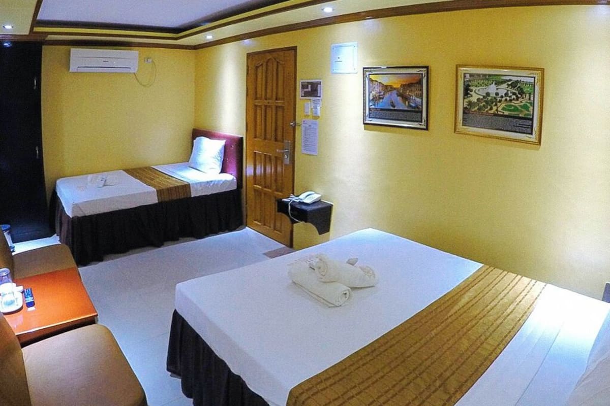 A hotel room with two beds, a desk, and a telephone.