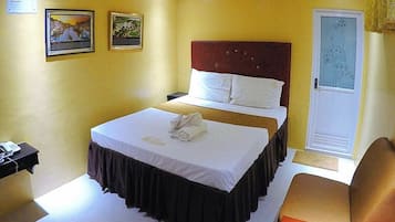 A hotel room with a bed, a nightstand, a chair, and a door with a frosted glass panel.