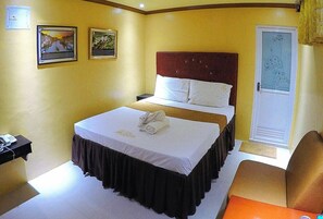 Habitación de hotel con cama, mesita de noche, silla y puerta con un panel de vidrio esmerilado.