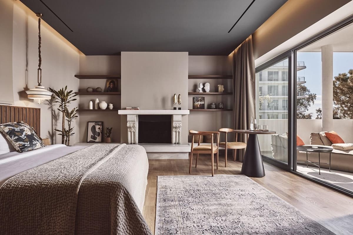 Ein modernes Schlafzimmer mit einem großen Bett, einem Kamin, einem Essbereich und einem Balkon mit Blick auf die Stadt.