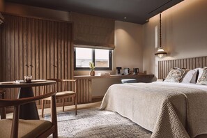 Una camera accogliente con un letto grande, un armadio in legno, un tavolino con sedie e una finestra con vista.