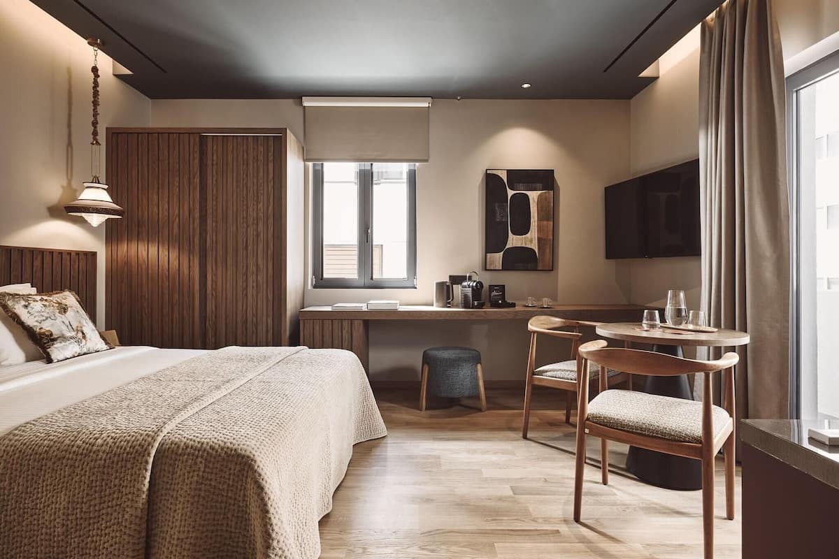 Ein modernes Hotelzimmer mit einem großen Bett, einem Schreibtisch, einem Stuhl und einem Fernseher.