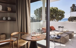 A modern living room with a round wooden table, a sofa, and a glass partition. - O2 Suites Glyfada (Glyfada)