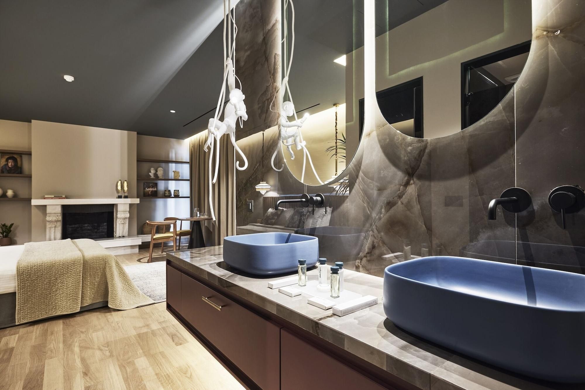 A modern bathroom with two large blue sinks, a marble vanity, and a large mirror.