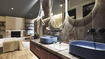 A modern bathroom with two large blue sinks, a marble vanity, and a large mirror.