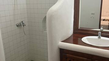 A bathroom with a shower, a sink, and a mirror.