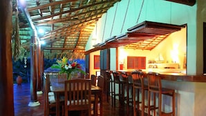 A wooden dining area with a high ceiling and a bar area in the background.