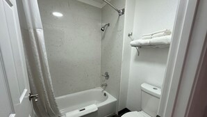 A bathroom with a bathtub, toilet, and shower. - Sands Motel (Livermore)