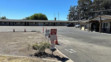Un estacionamiento con un motel al fondo, un letrero de estacionamiento privado y un aviso.