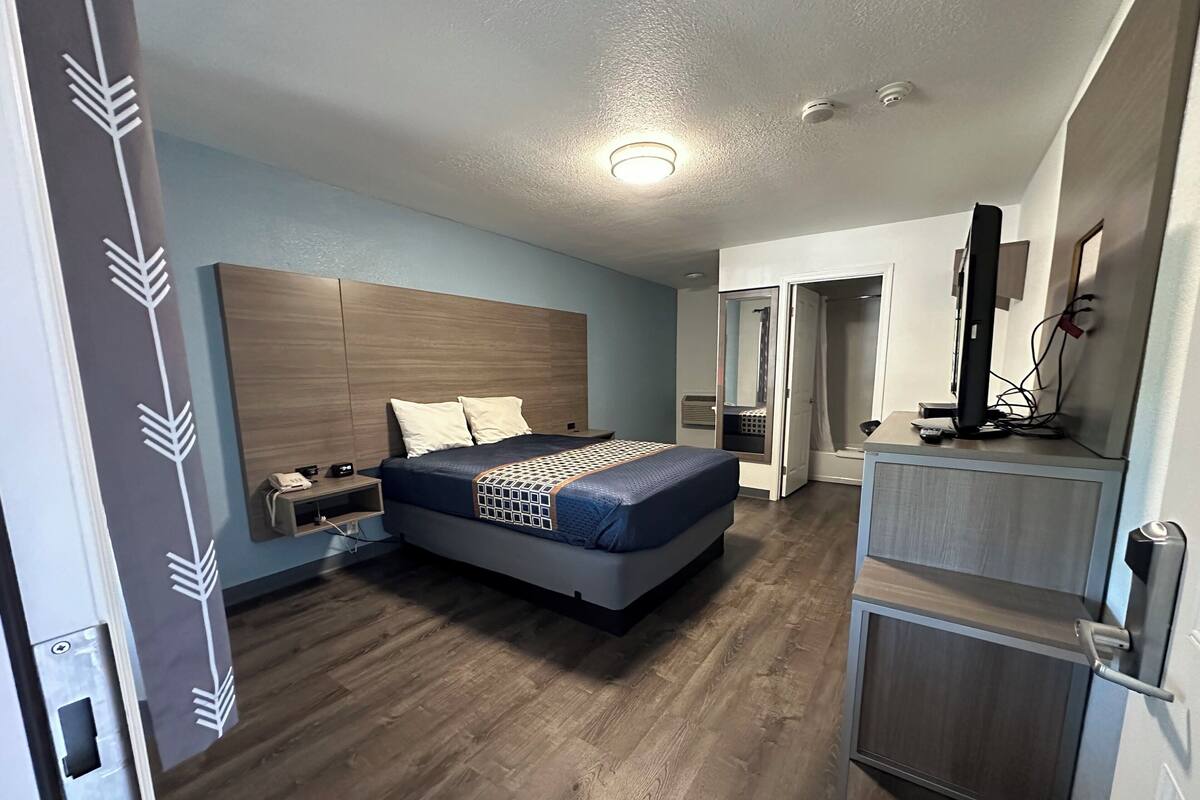 A bedroom with a bed, bedside table, and a TV.