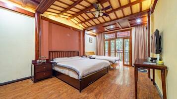 Quarto com teto de madeira, duas camas, mesa de cabeceira, televisão e janela com cortinas.