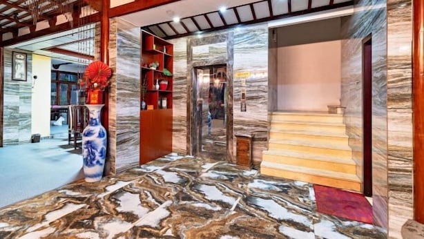 A lobby with a marble floor, wooden beams, a red vase, and a staircase. - Yangshuo wanglai Hotels (Yangshuo)