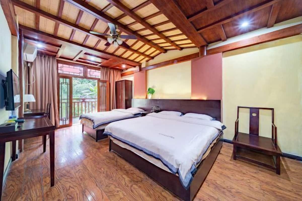 A hotel room with two beds, a wooden floor, a ceiling fan, and a TV.