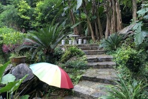 A stone staircase surrounded by lush greenery and a colorful umbrella.