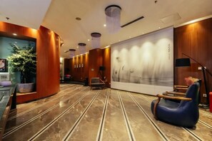 Eine Hotelhalle mit einer Rezeption, einer Sitzecke und einem großen Wandbild.