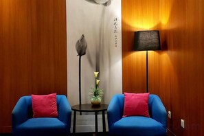 A room with two blue chairs, a small table with a lamp, and a decorative plant. - Starlight Holiday Hotel (Zhengzhou Erqi Square Dongda Street Subway Station Branch) (Zhengzhou)