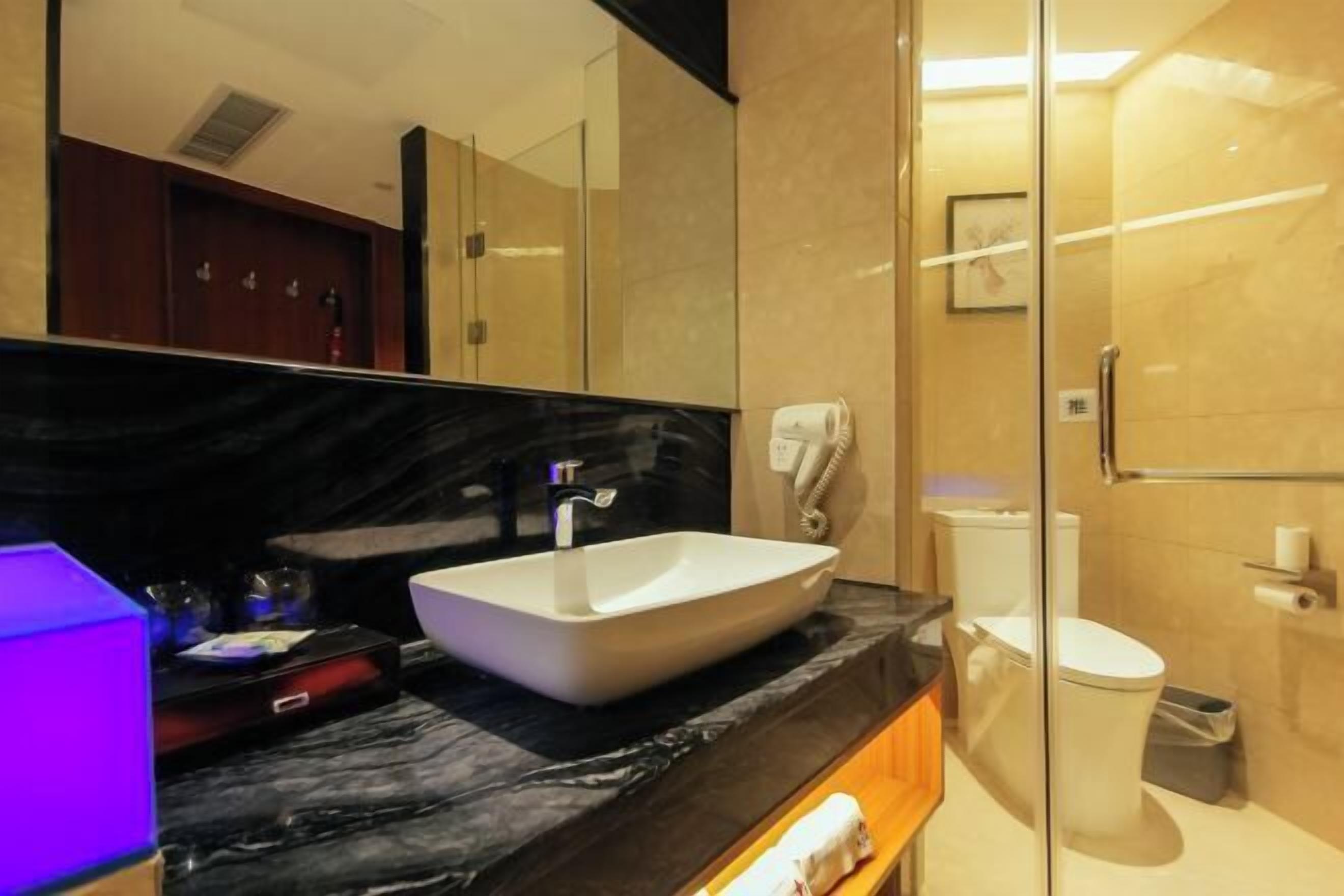 A modern bathroom with a large mirror, a white sink, a glass shower enclosure, and a toilet.