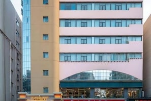 Un hotel de varios pisos con diseño moderno, que destaca una entrada arqueada y una serie de ventanas en cada nivel.