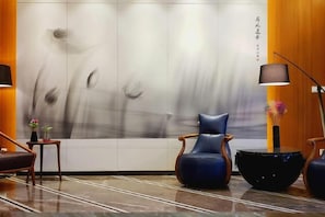 Un interior moderno con zona de estar, una pared con arte abstracto y un suelo reflectante.